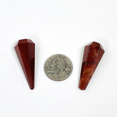 2 Red Jasper Pendulum Points next to quarter for size comparison on white background