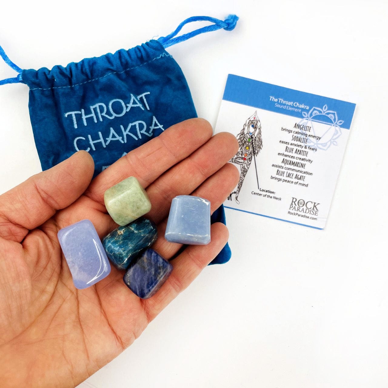 The Throat chakra stones in a hand with the pouch and information card behind