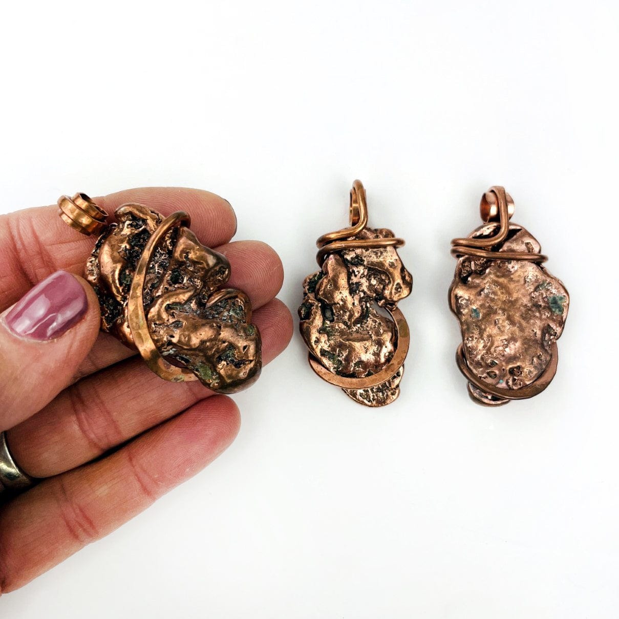 3 Copper Nugget freeform pendants with one in a hand for size reference