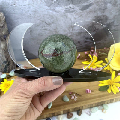 Acrylic Sphere Holder Crescent Moons in a hand. Acrylic Sphere Holder Crescent Moons is holding a sphere.