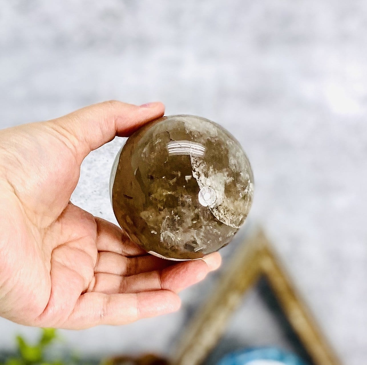 smokey quartz polished sphere in hand for size reference