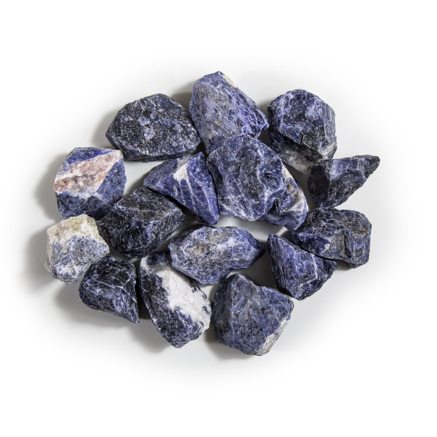 overhead view of many sodalite rough stones in a pile on white background