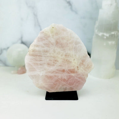 Rose Quartz on Metal Stand with other crystals blurred on marble background