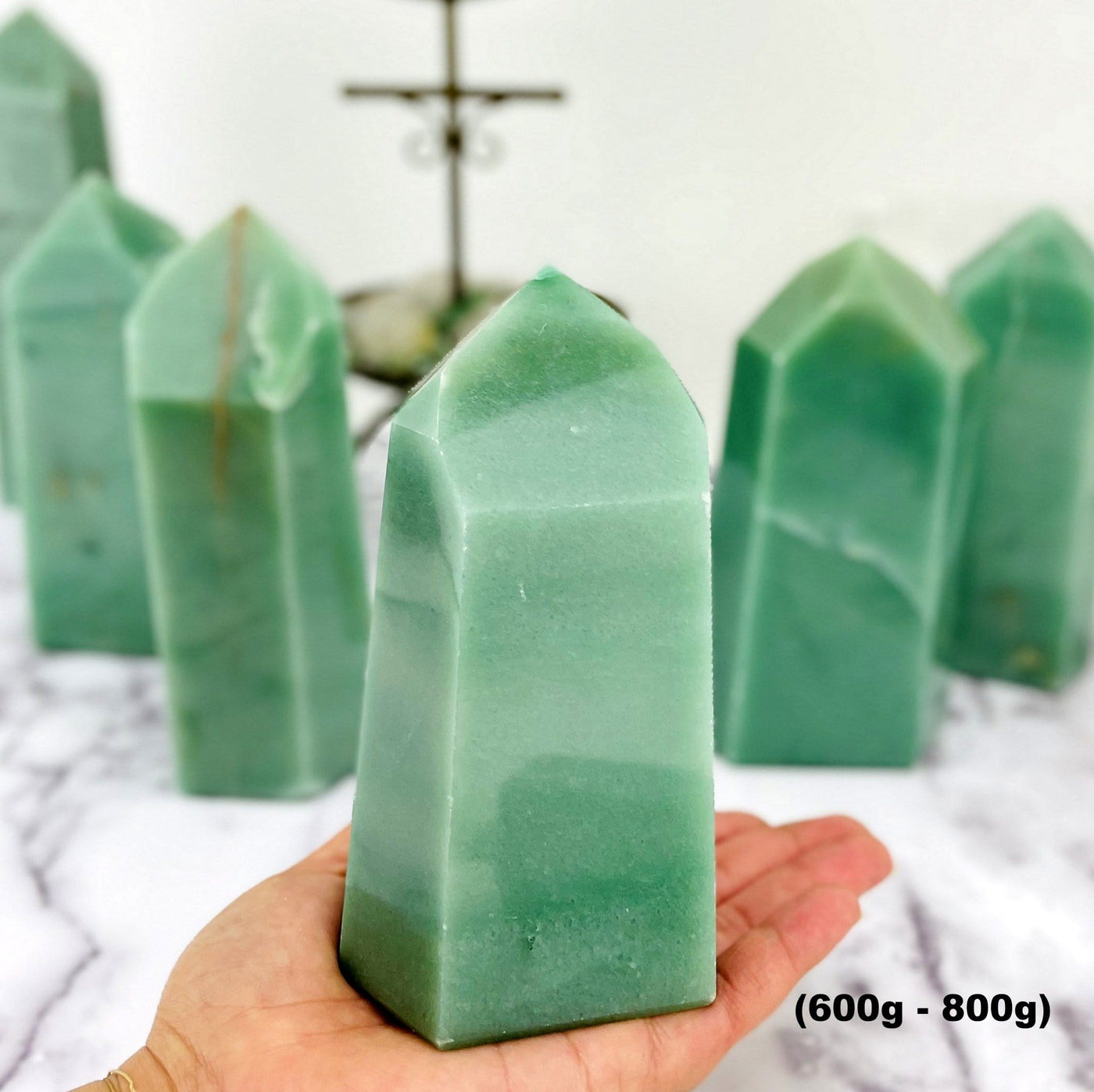 600-6009 green quartz tower in the palm of a woman' shand with other towers in the background.