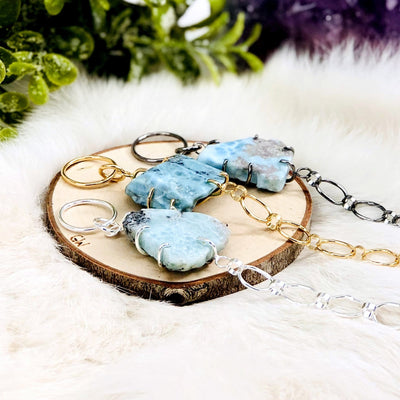 angled shot of 3 Larimar Bracelets in different metals with decorations in the background