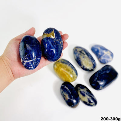 two 200g - 300g sodalite large tumbled stones for size reference with many others in white background for possible variations