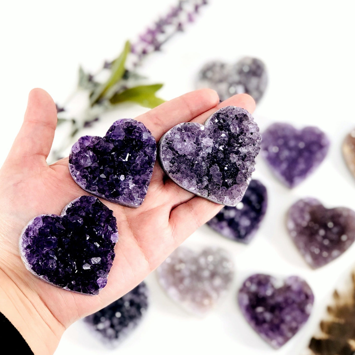 hand holding up amethyst hearts with decorations in the background