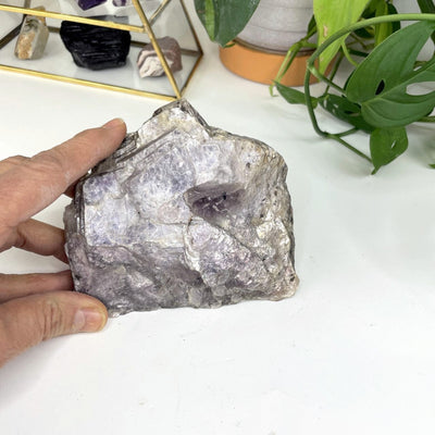 Lepidolite Mica Chunk on display near a hand for size reference