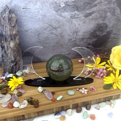 Acrylic Sphere Holder Crescent Moons holding a sphere within an alter surrounded by crystals and flowers.
