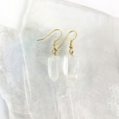 Close up of gold plated crystal point earrings on a selenite slab.