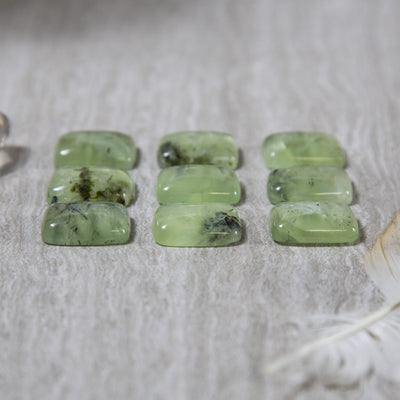 side view of 9 prehnite cabochons on gray background