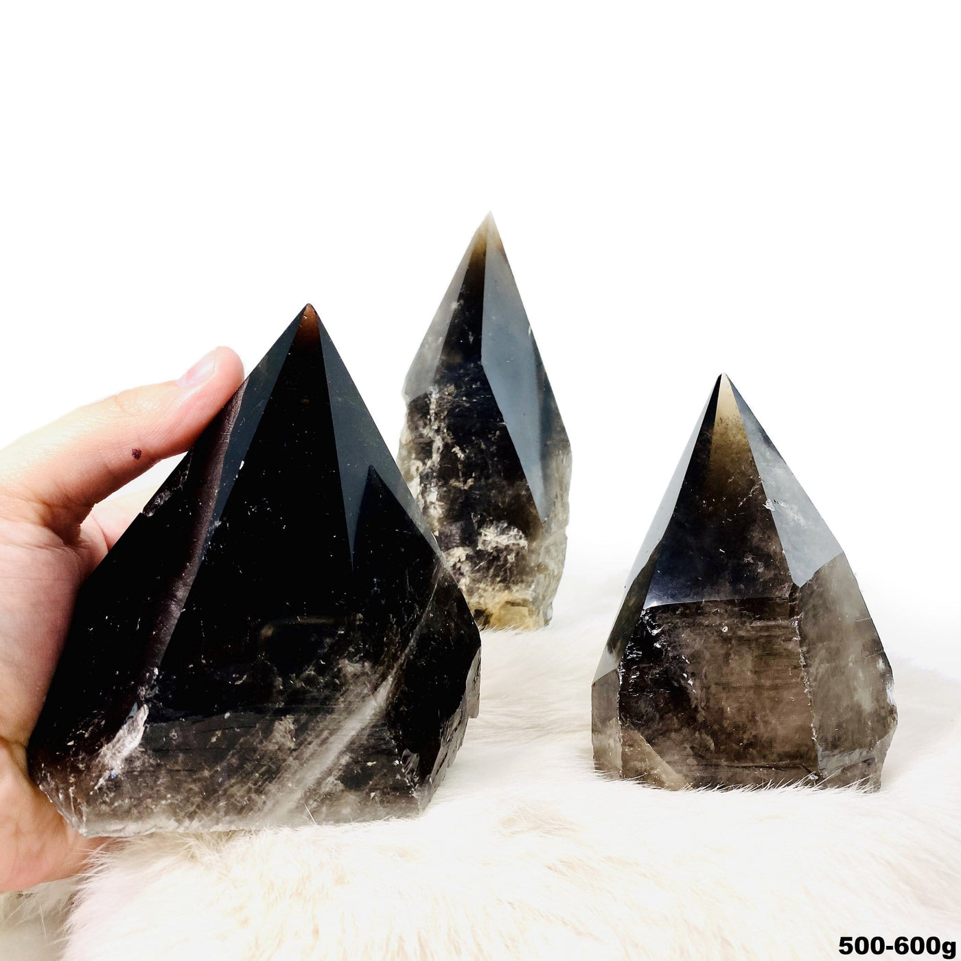 three 500g - 600g smokey quartz semi polished points on display for possible variations with one in hand for size reference