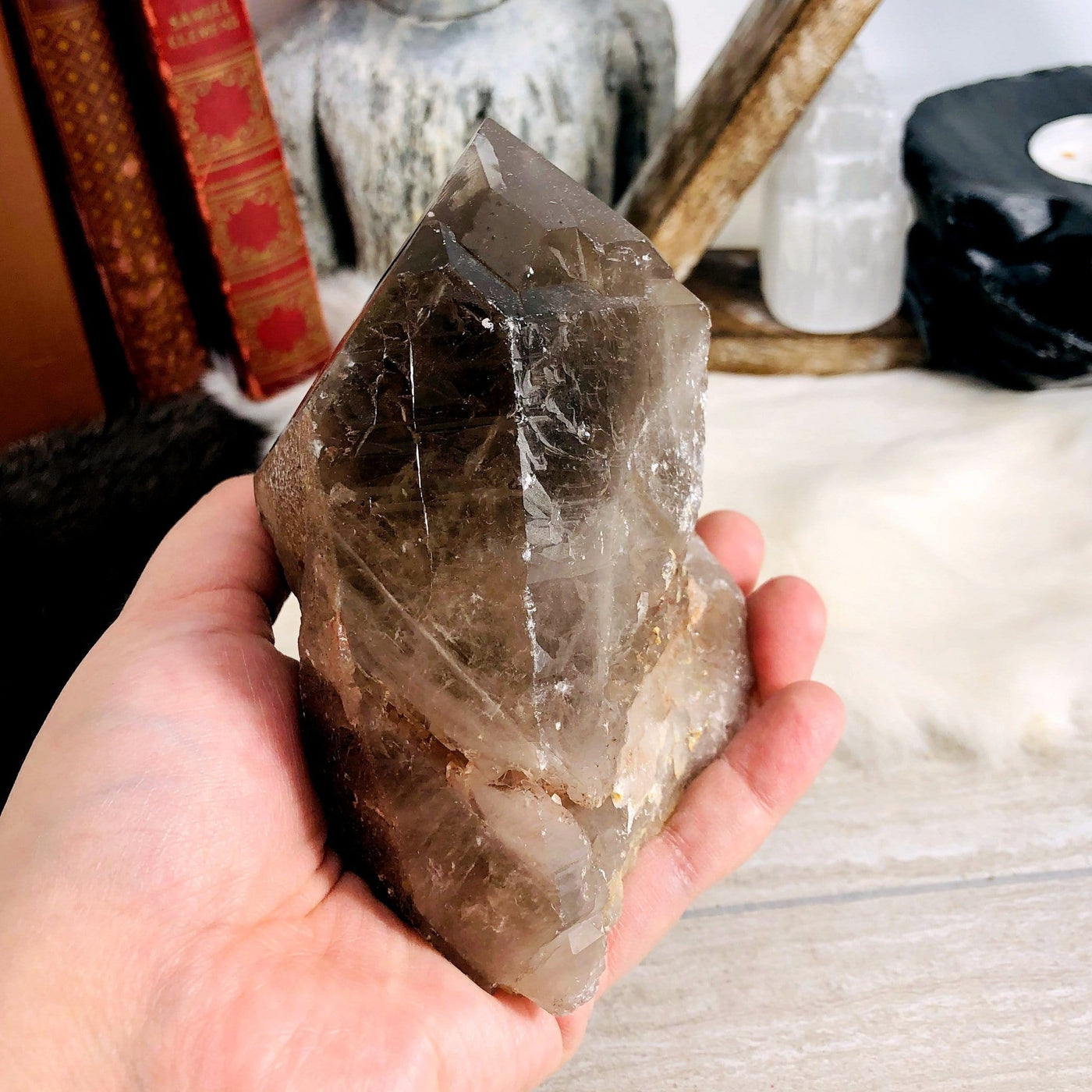 side view of smokey quartz natural point in hand in front of backdrop for thickness