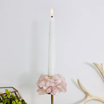 Rose Quartz Taper Candle Holder with lit candle on white background