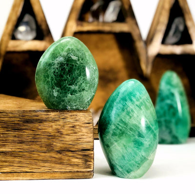 2 Green Fluorite Polished Cut Bases with another blurred in the background with decorations