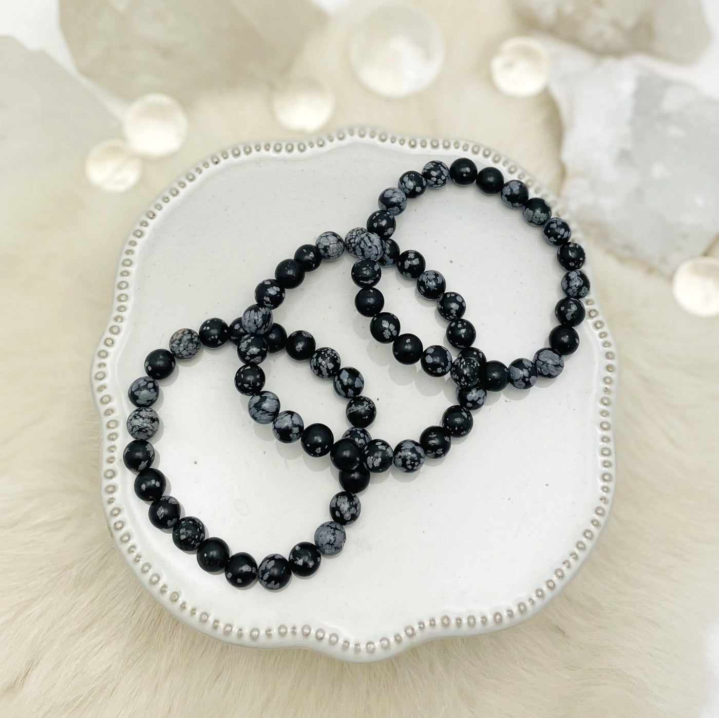 overhead view of three snowflake jasper round bead bracelets on display for possible variations