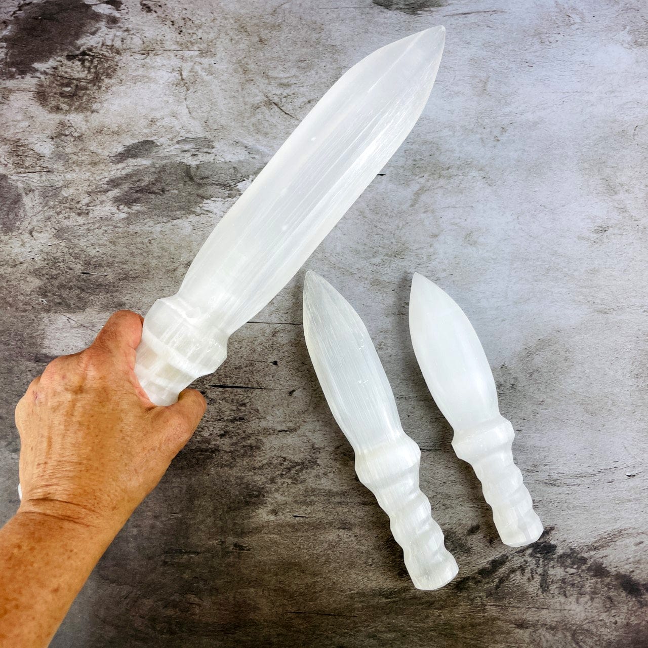 3 sizes of Selenite Knife with Twisted Handles, with the large one in a hand for size reference