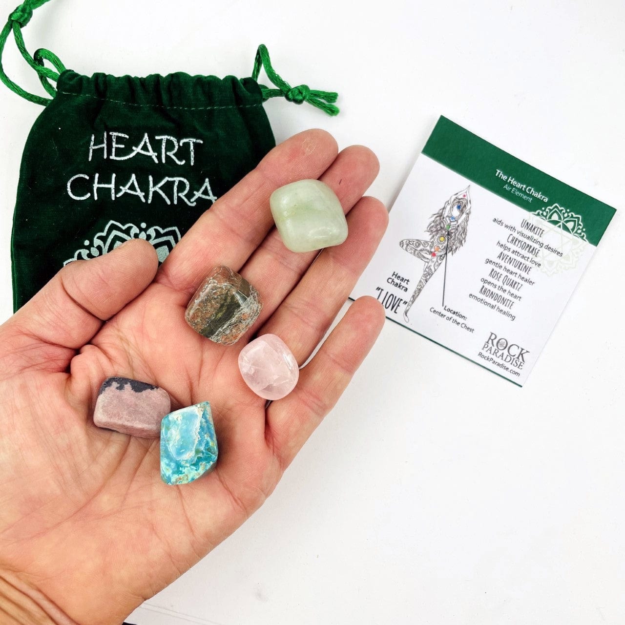 The Green Heart Chakra set opened up with the tumbled stones in a hand with the information card and pouch behind