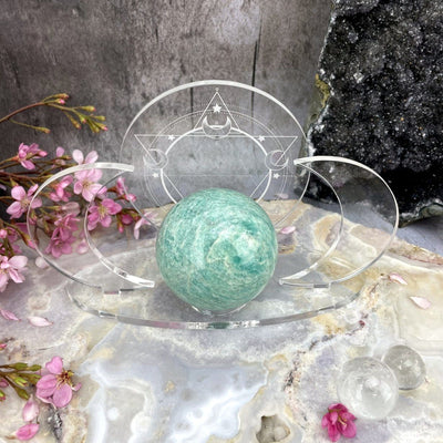 Shown from atop - Acrylic Sphere Holder Crescent Moons - Six Pointed Star holding a sphere in an alter surrounded with crystals and flowers.