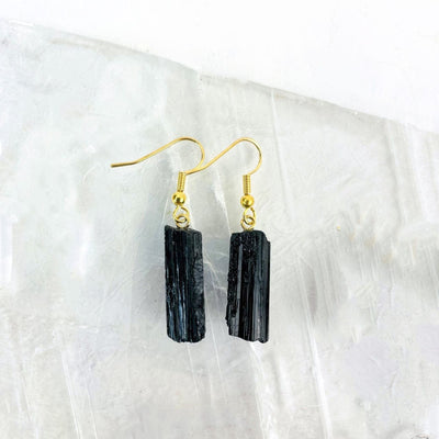 Close up of black tourmaline earrings gold plated on a selenite slab.