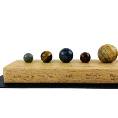 Close up of 5 of the stone spheres representing planets on a wood base with stone names
