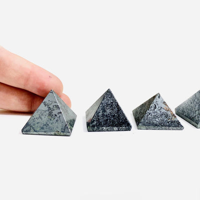 multiple hematite pyramids shown with fingers in picture to show difference in size and design