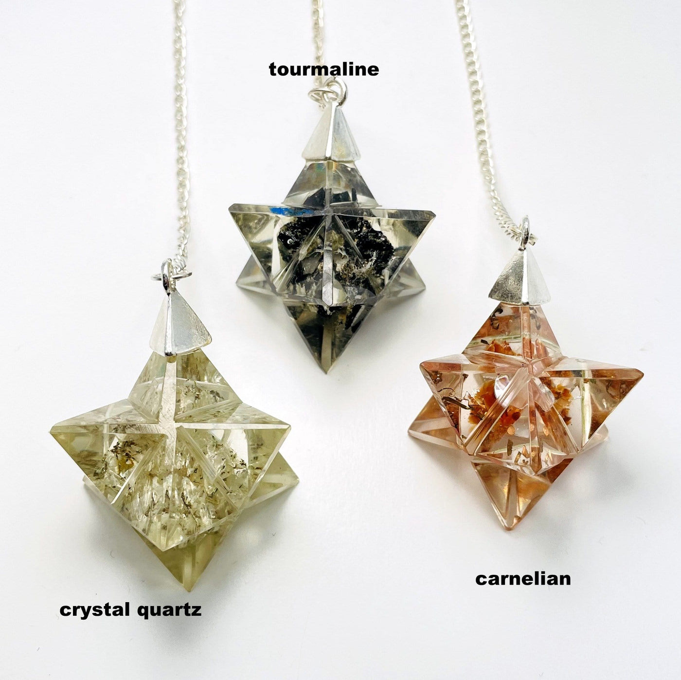 crystal quartz, tourmaline, and carnelian orgone merkaba star pendulum on white background