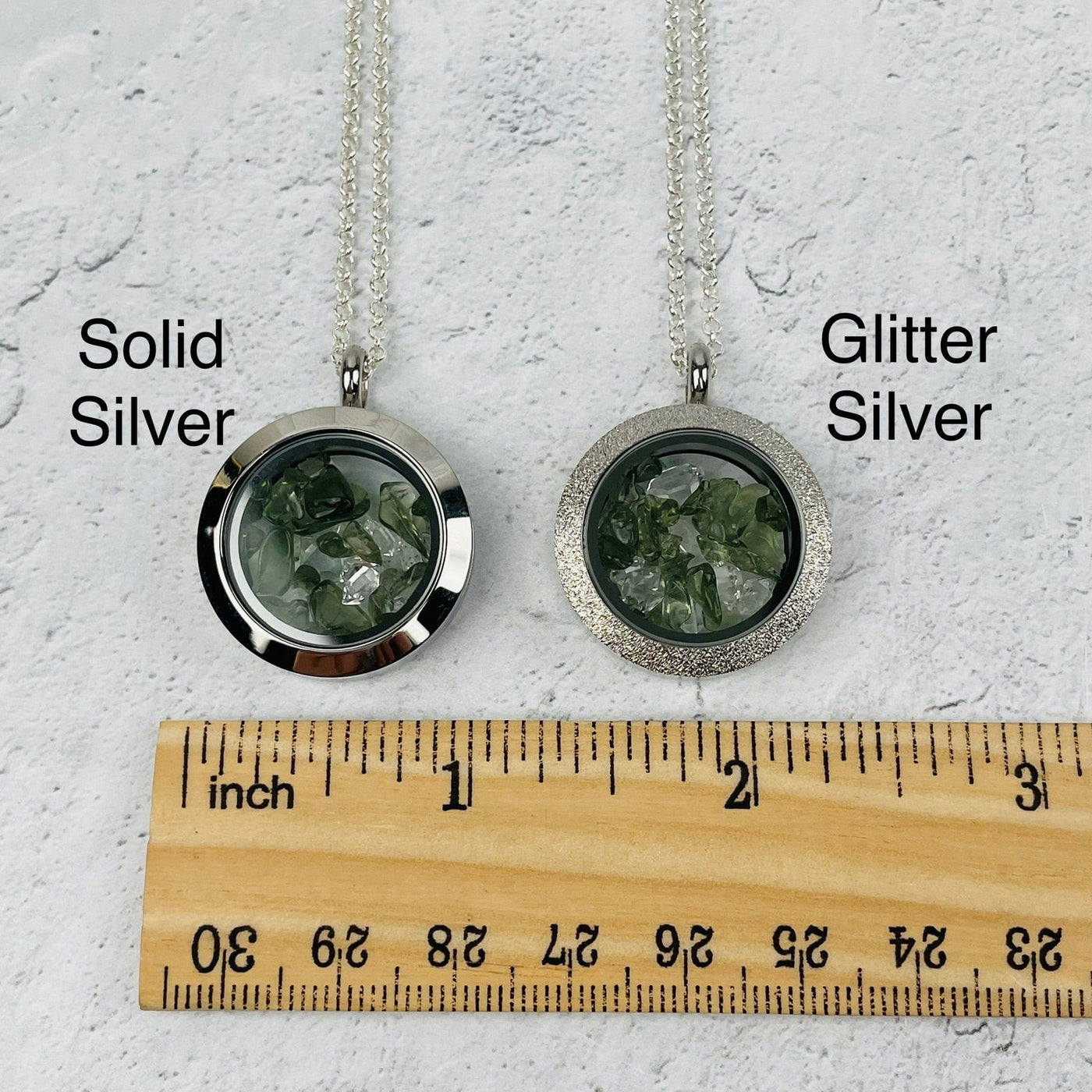 pendants next to a ruler for size reference. available in solid silver or glitter silver 