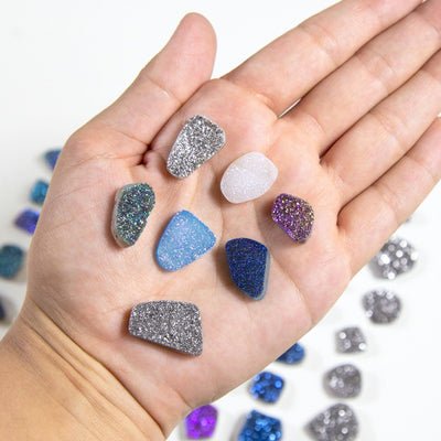 titanium beads displayed in hand for size reference