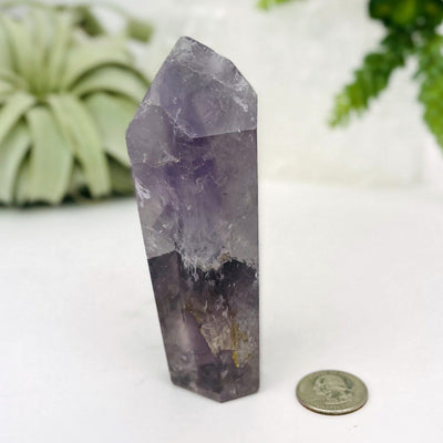 Amethyst Polished Point next to a quarter for size reference