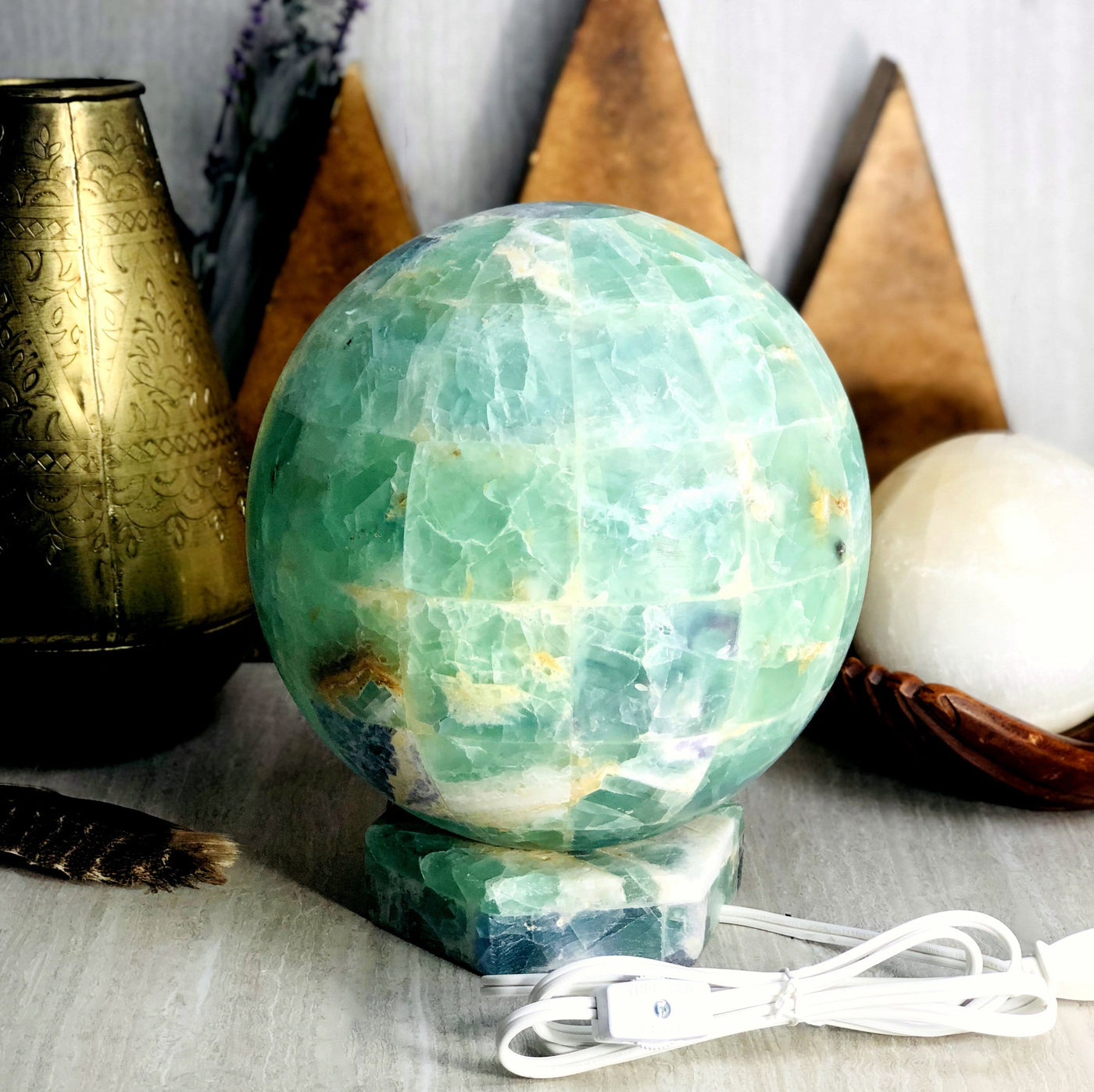 Rainbow Fluorite Sphere Lamp and electric cable with various decorations in the background