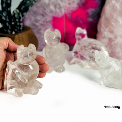 hand showing 150-300g Crystal Quartz Cat Mini Statue with others in the background
