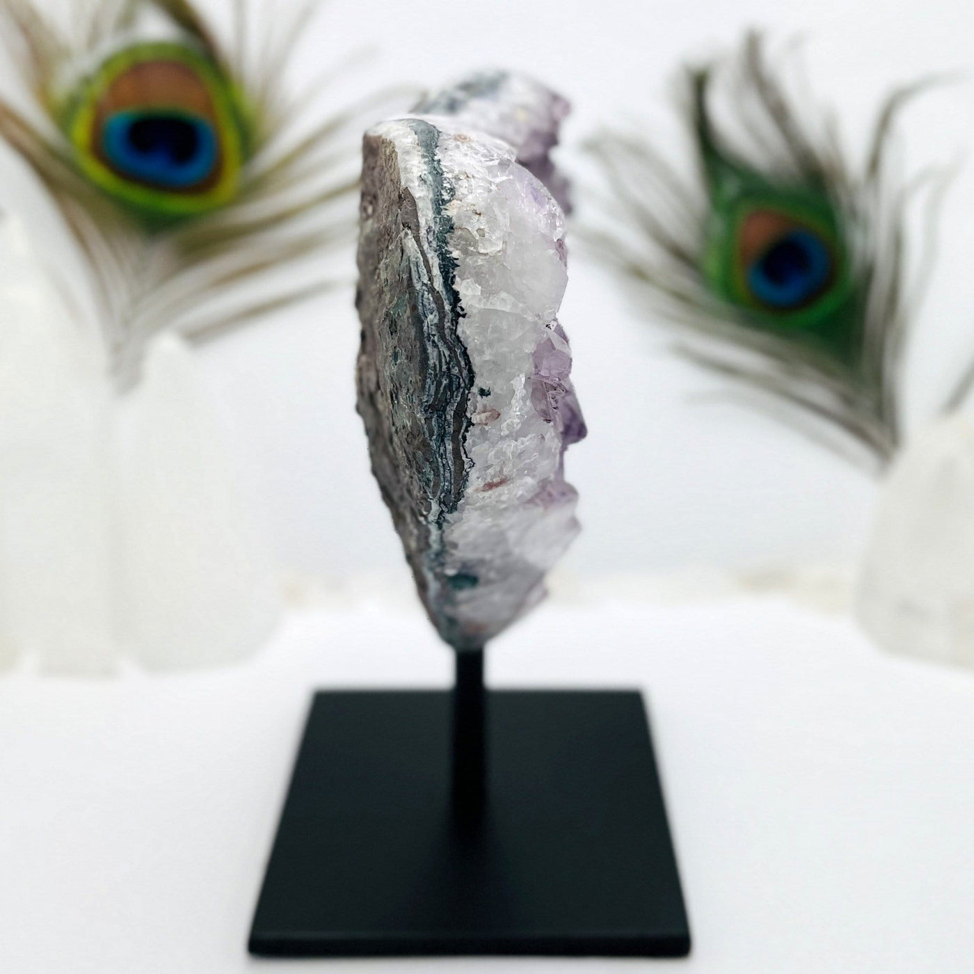 side view of Amethyst Cluster on Metal Stand with decorations in the background