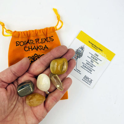 The Yellow Solor Plexus Set opened up with the stones in a hand and the information card and pouch behind.