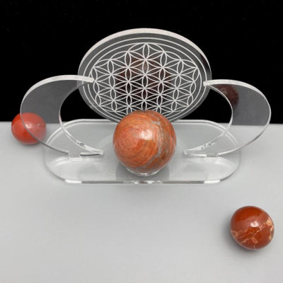 Acrylic Sphere Holder - Crescent Moons with Flower of Life displayed from above in an alter holding a sphere. A few spheres surrounding the holder.