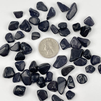 Blue Goldstone Tumbled Chips next to a quarter for size reference 