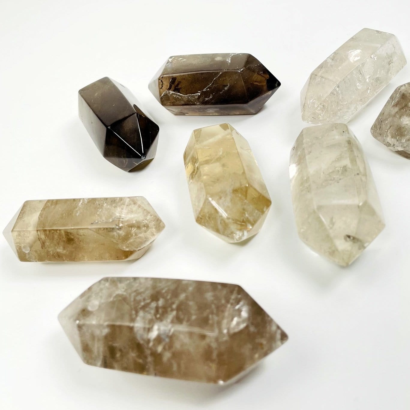 many large drilled smokey quartz double terminated point in a pile on white background