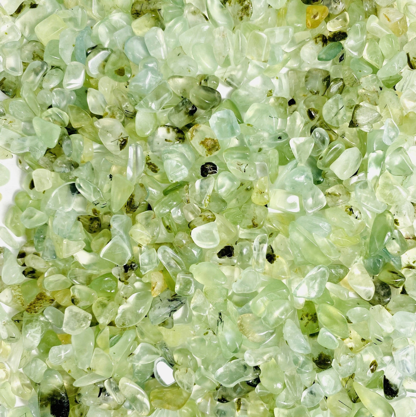 close up of green prehnite chips on a white background
