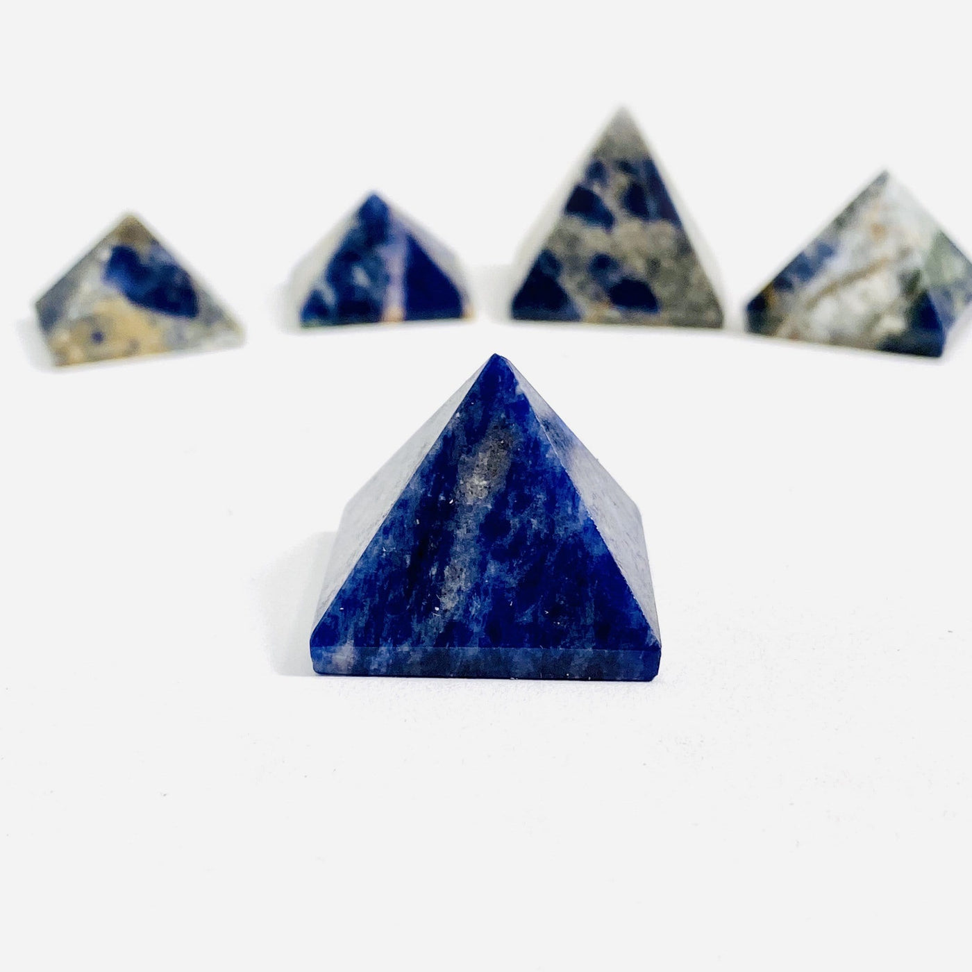 close up of one sodalite pyramid on a white background with four others in the background