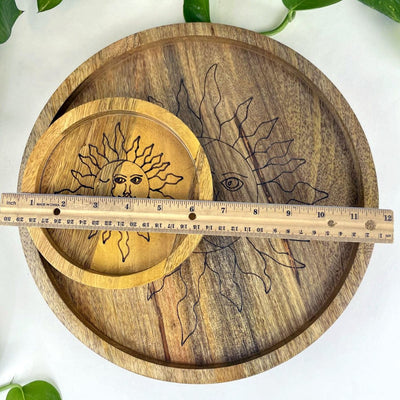 large and small mango wood trays stacked on each other with a ruler on top to show size.  Small is approximately 6" round and large is approximately 12"
