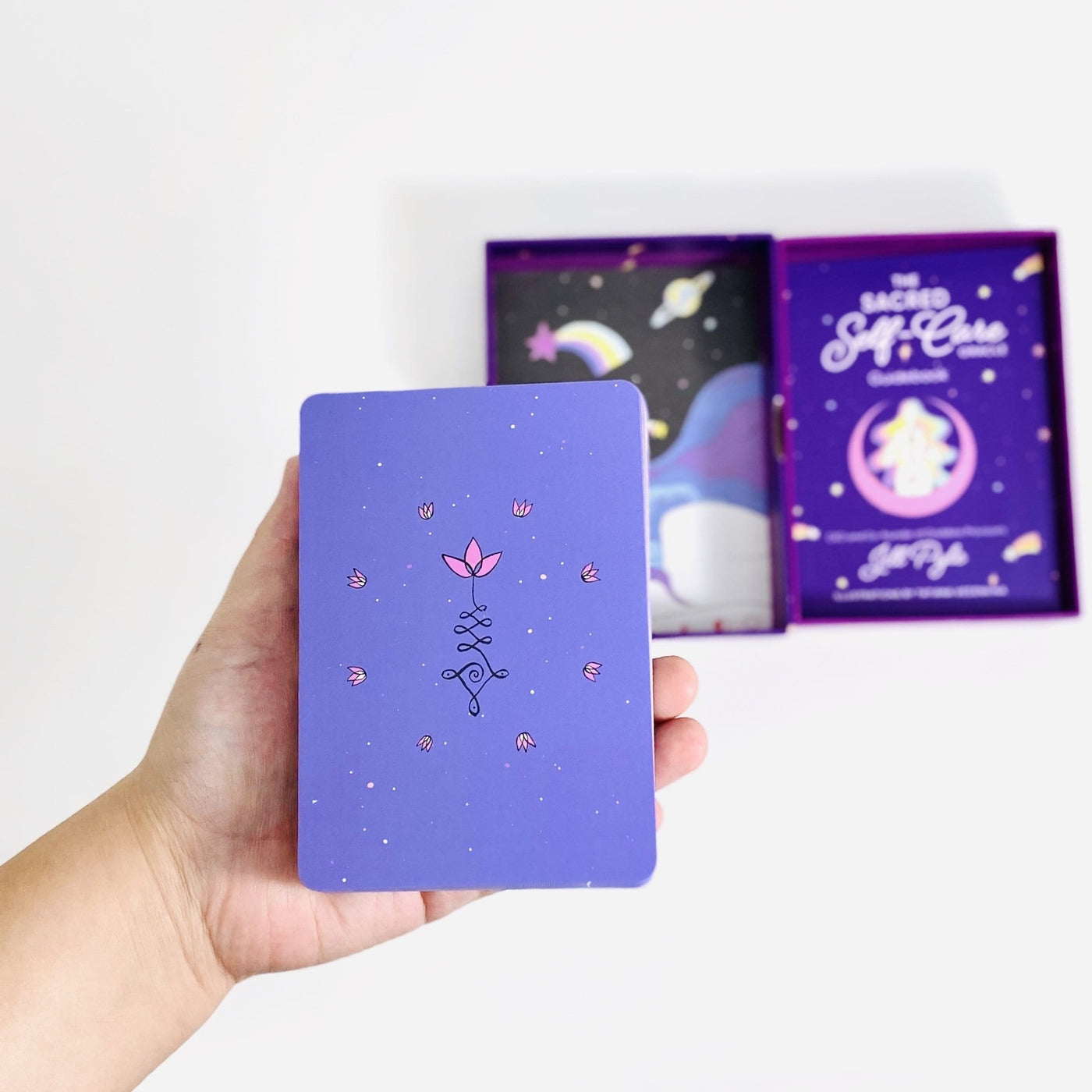 Hand holding the beautiful purple deck of cards with a small pink design 