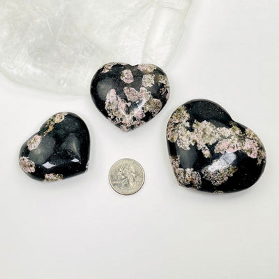black jade with pink thulite hearts next to a quarter 