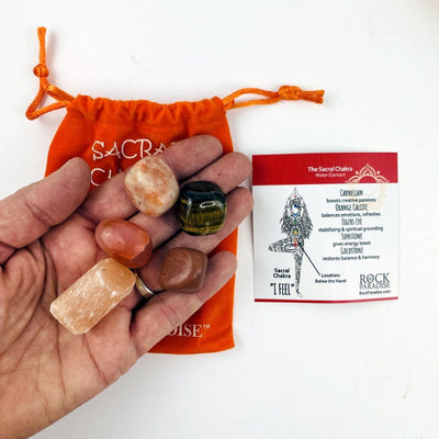 The Sacral Chakra set opened up with the tumbled stones in a hand and the information card beside. 