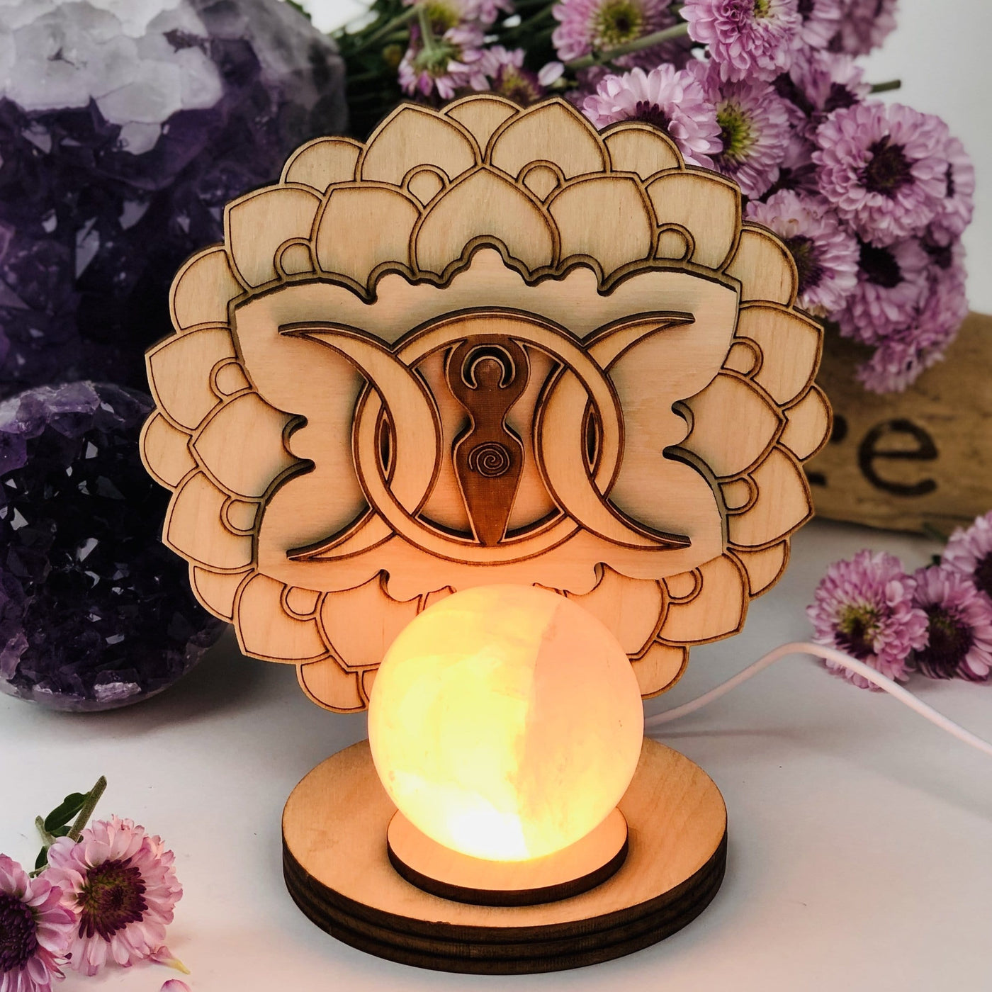 Earth Goddess and Moon Wooden Sphere Stand Lamp with the light on on a flower background 