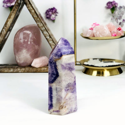 side view of Chevron Amethyst Polished Point with decorations in the background