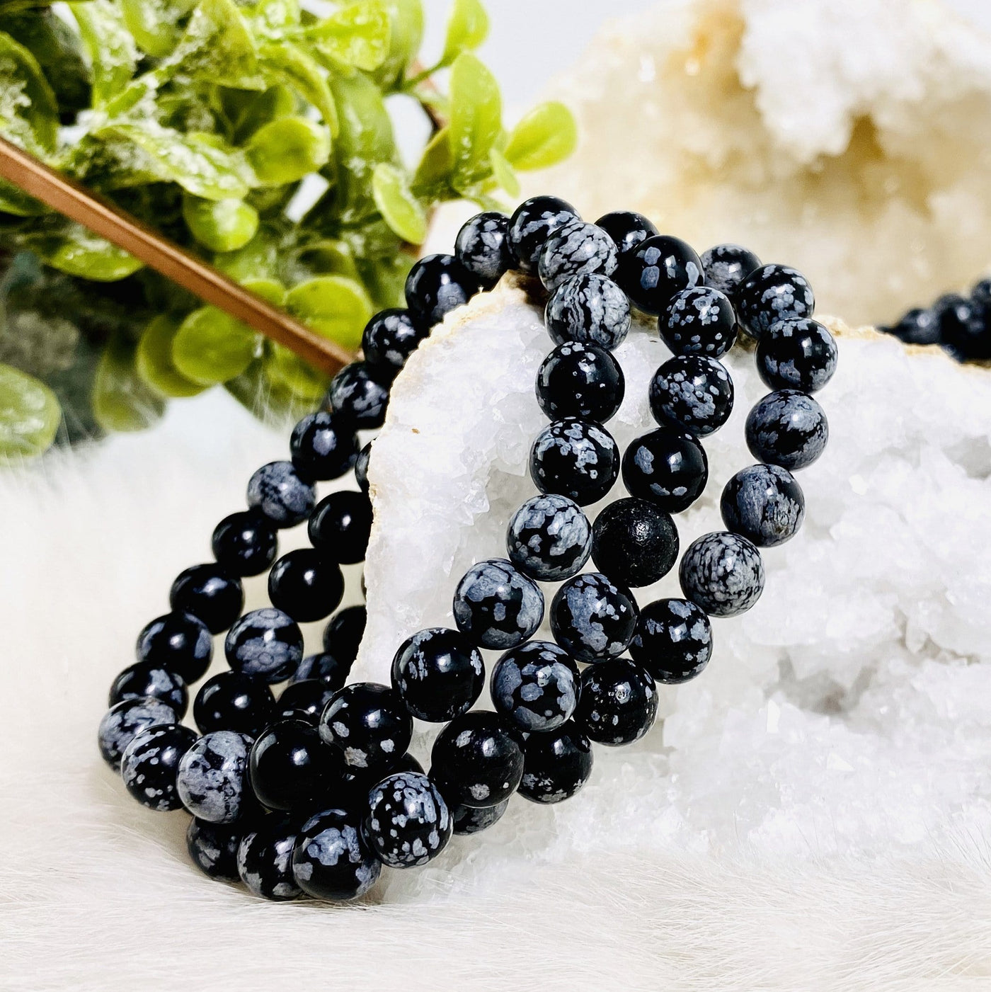 three snowflake obsidian round bead bracelets on display