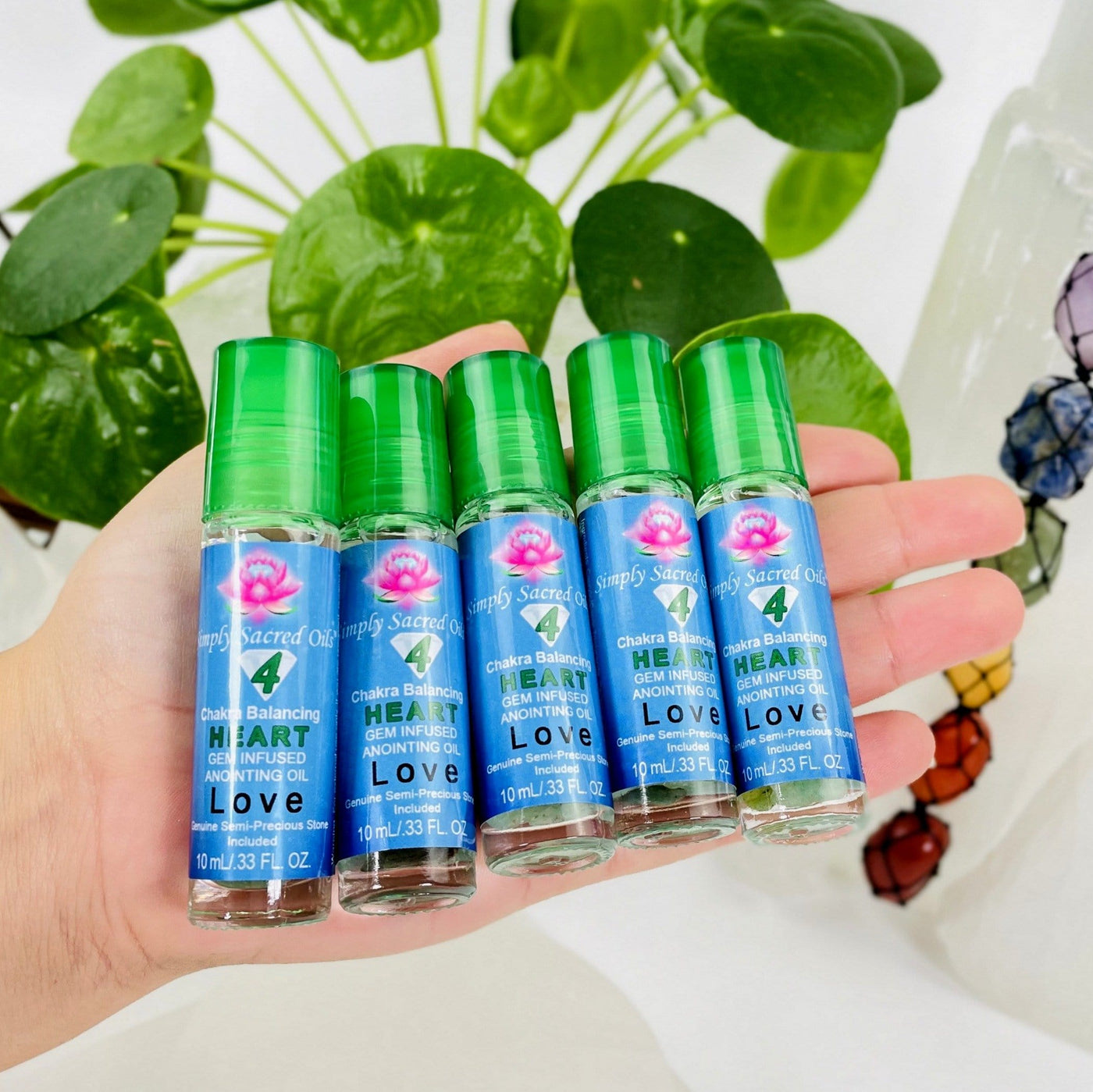 multiple heart chakra balancing oil pictured in hand to show size reference
