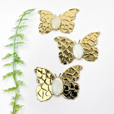 gold butterfly pendants with a mother of pearl center 