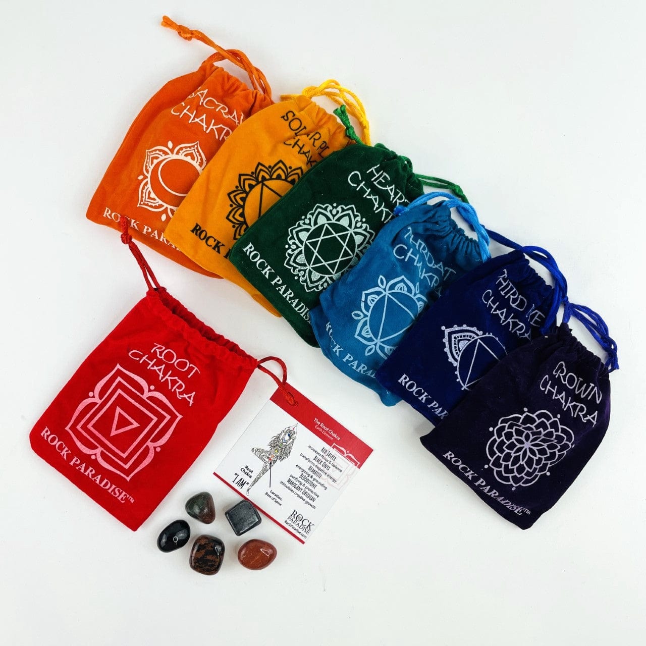 The Root Chakra Pouch with the card and stones next to it, and all the other sets behind