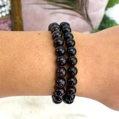 wrist wearing garnet bracelets with decorations in the background